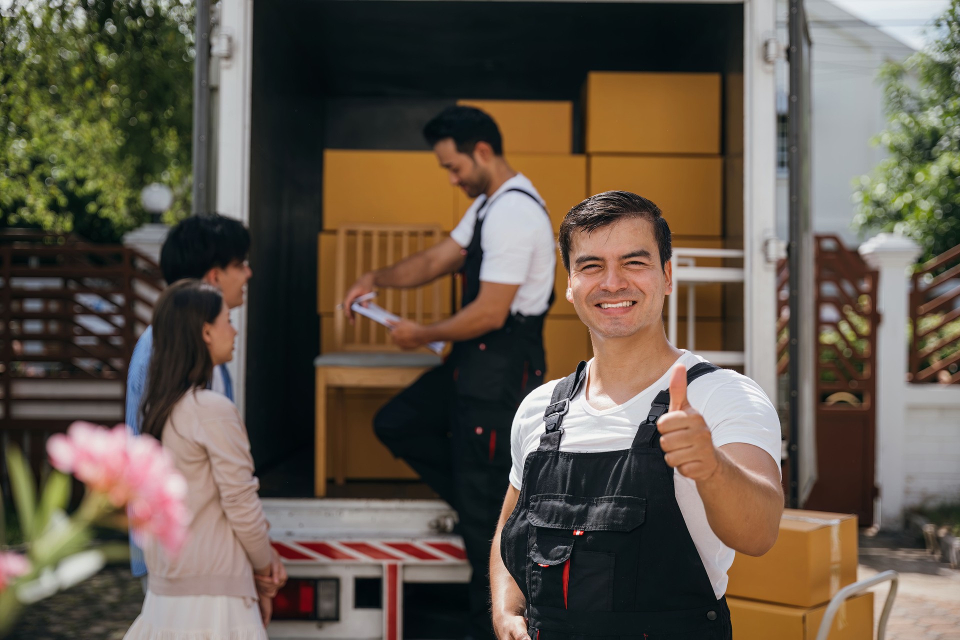 A smiling mover captured in a portrait unloads boxes into a new home from a truck. These removal company workers guarantee efficient moving and happiness. Moving day concept